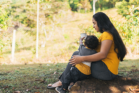 a woman drinking coffee in a white cup with her son in a natural environment