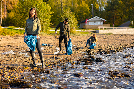  Volunteers are cleaning garbage in bag at beach on sunny day