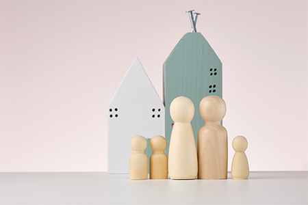 wooden figures of men and a miniature house on a beige background