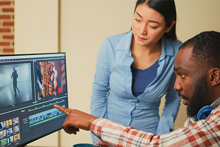Creative filmmakers doing teamwork to edit video footage in agency studio