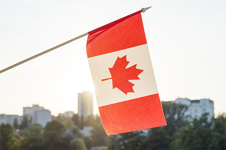 Flag of Canada from window on sunset background