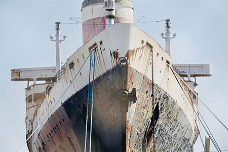 A large old rusty industrial ship under the sunlight and a blue sky