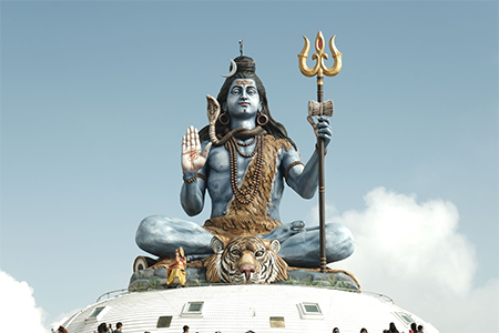 A majestic statue of Lord Shiva seated on a tiger skin against a clear sky, showcasing intricate det