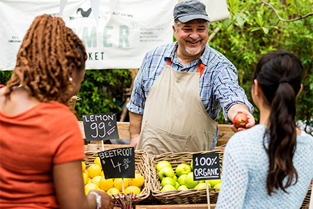 people buying organic vegetables outdoors at local farmers market