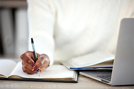 woman making notes in a book while studying