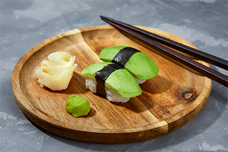 Sushi covered with avocado on wooden board gray stone background