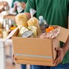 Volunteer holding donation box with food in charity center, closeup