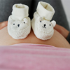 Baby shoes on pregnant abdomen of future mom