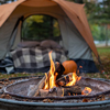 Closeup of campfire in evening with cozy orange tent in background