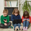 Children sit on the floor and use electronics
