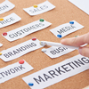 cropped view of a person pointing with pencil on branding inscription on cork board