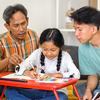 Father And Brother teaching Little Girl Doing Homework On Table While Sitting On The Floor