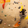 Sporty little girl climbing artificial boulder on practical wall in gym
