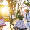 group of four  adults dressed as huaso dancing cueca in the town square at sunset