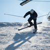 Skier in the moment of falling on the snowy slope with a ski lifts and blue sky