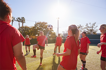 Womens Football Team Kicking Ball Whilst Training For Soccer Match