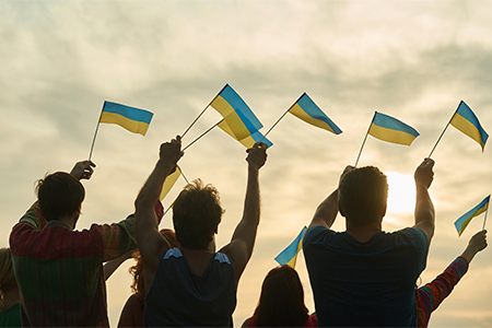 Young people waving ukraininan flags, back view. People with Ukraine flags silhouette, down sky back