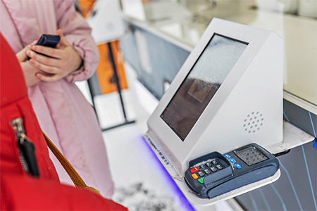 a woman paying at self checkout kiosk