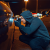 Car thief with screwdriver breaking door lock. Hooded male robber opening vehicle on parking