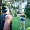 Three people are exercising in a park, personal trainer is holding a class with his athletes