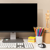 Workspace showing computer with black blank screen, keyboard, mouse and various stationery items