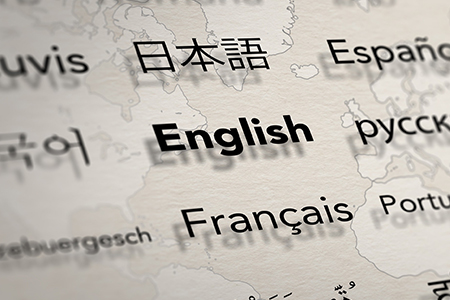 Several important languages on paper with world map background. Depth of field image. Translate and 