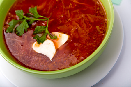 Green bowl of bright red Borsch with garnish