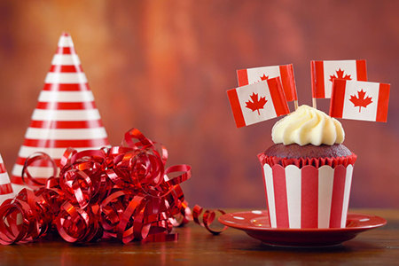 Red and white theme cupcakes with Canadian maple leaf flags for first of July Canada Day or Canadian
