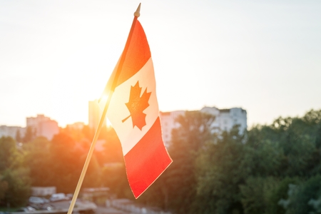 Flag of Canada from window on sunset background