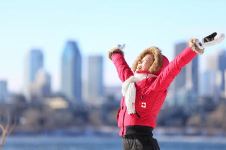 woman in canada parka raising arms and smiling