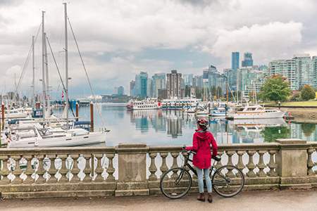 Stanley Park - woman with cycle standing on a bridge over water