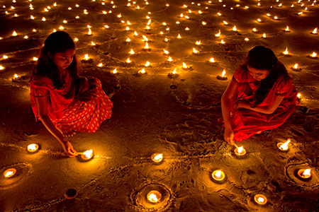 two women lighting diwali candles