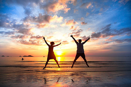 Young couple in a jump on the sea beach at sunset concept of long-awaited vacation
