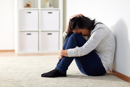 people, grief and domestic violence concept - unhappy woman sitting on floor and crying at home