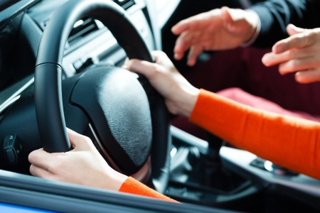 focus on driver hands on steering wheel. instructor guiding driver