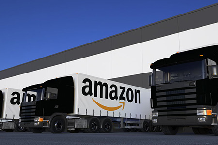 Freight semi trucks with Amazon.com logo loading or unloading at warehouse dock. Editorial 3D render