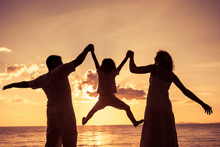 Silhouette of happy family who playing on the beach at the sunset time. Concept of friendly family.