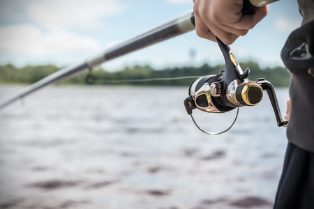hand holding a fishing rod with reel. Focus on Fishing Reels
