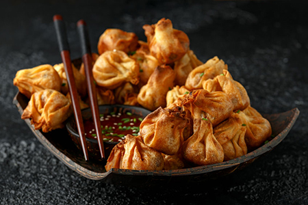 Chinese takeaway finger food Vegetable wontons with sweet chilli dip sauce and chop sticks.
