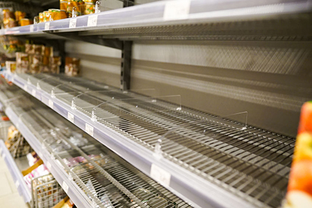 empty shelves with few canned goods left in a supermarket