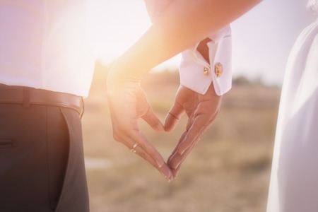 Holding Hands with wedding rings on the background of sunlight