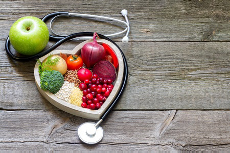 heart shaped bowl filled with healthy snacks, such as fruit. Wrapped in stethoscope 