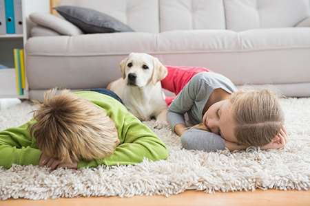 Cute silblings with their puppy on rug at home in the living room