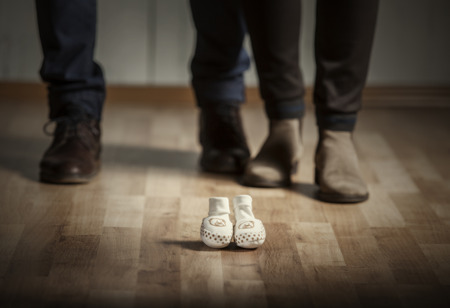 parents standing with baby boots on floor