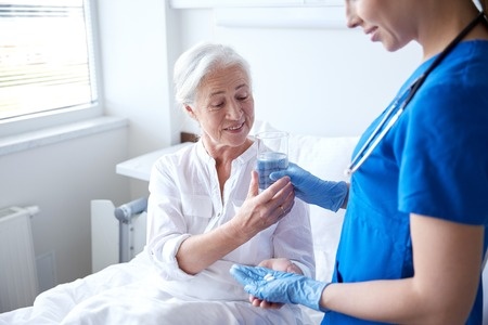nurse helping elder patient take medication