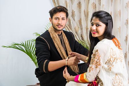  young sister tying traditional Rakhi Thread on brother's wrist
