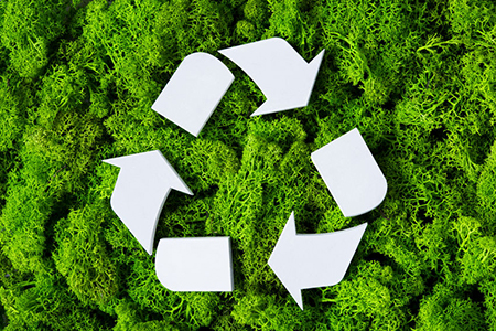 Top view of white recycle eco symbol on green moss with copy space. High angle view of recycled sign