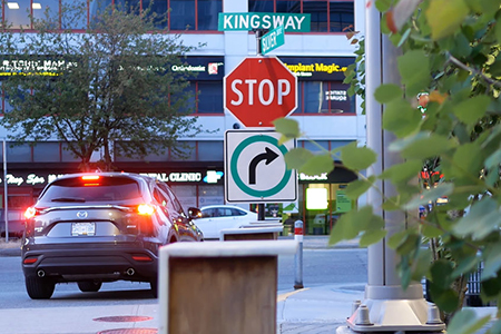 Burnaby, BC, Canada - May 30, 2018 : Motion of stop sign on sidewalk with blur traffic flow in Burna