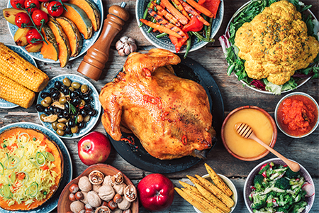 Roasted whole chicken, rice, pumpkin, corn, honey, nuts, vegetable salads over wooden background