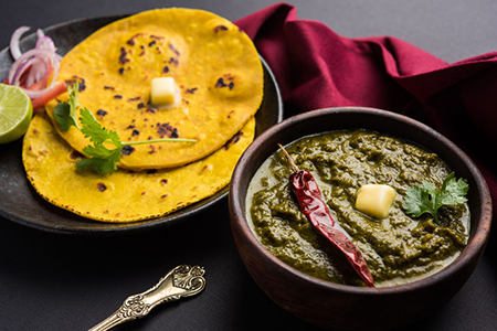 Sarson Ka Saag served with roti in dark coloured dishes